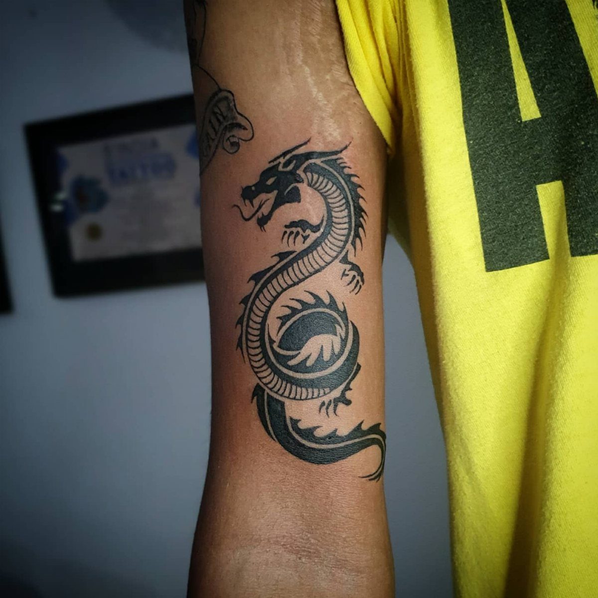 Tribal dragon tattoo with bold black lines on a man's upper arm