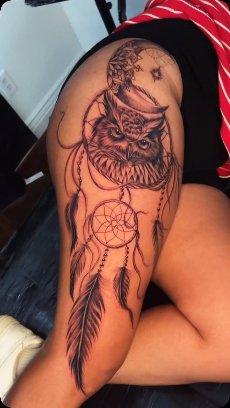 Dreamcatcher tattoo with an owl and crescent moon on a person's thigh.