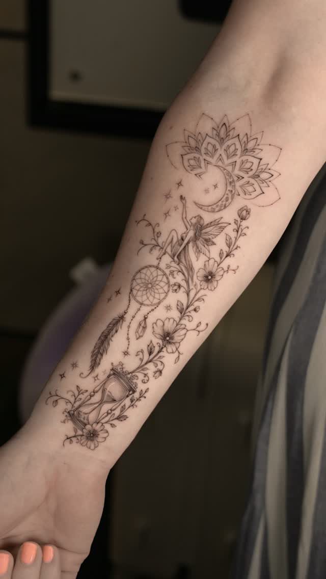 Forearm tattoo featuring a crescent moon, dreamcatcher, fairy, and an hourglass design.