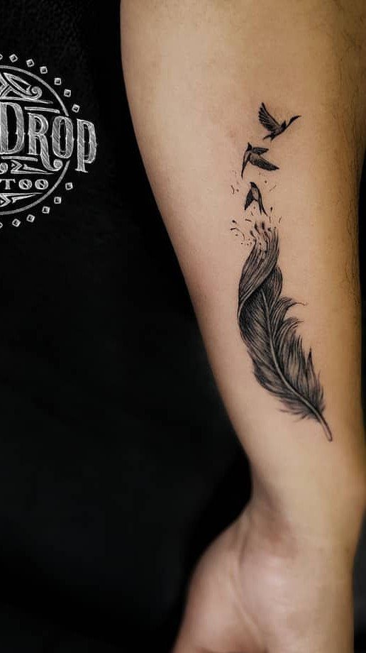 Feather tattoo on forearm transitioning into three small birds flying upwards
