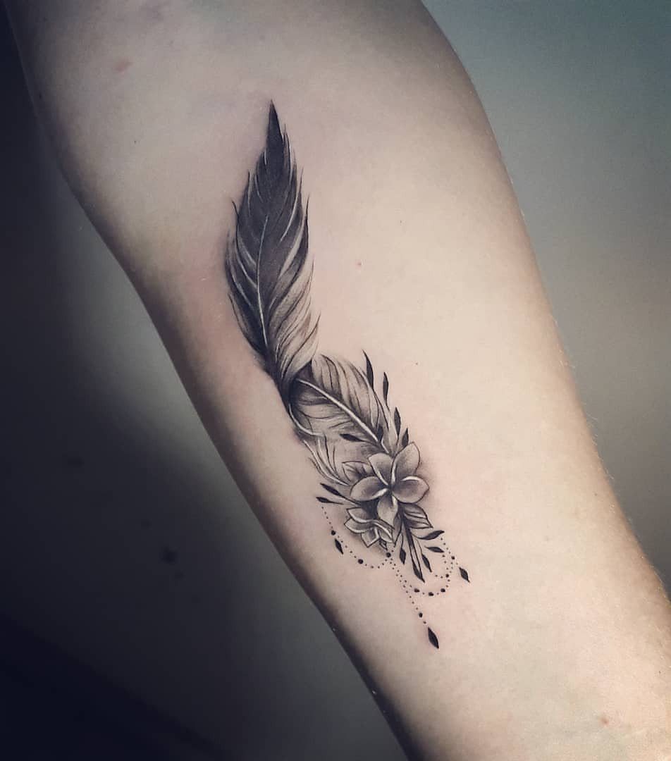 Feather and flower tattoo in black and grey ink on a forearm