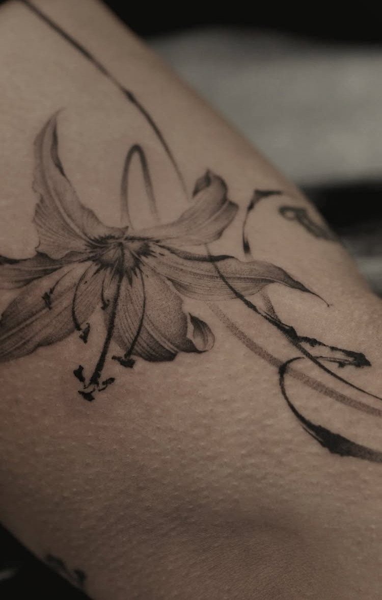 Lily flower tattoo with fine lines and flowing curves on human skin
