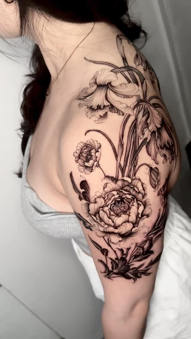 Detailed black and grey floral tattoo on a person's shoulder and upper arm.