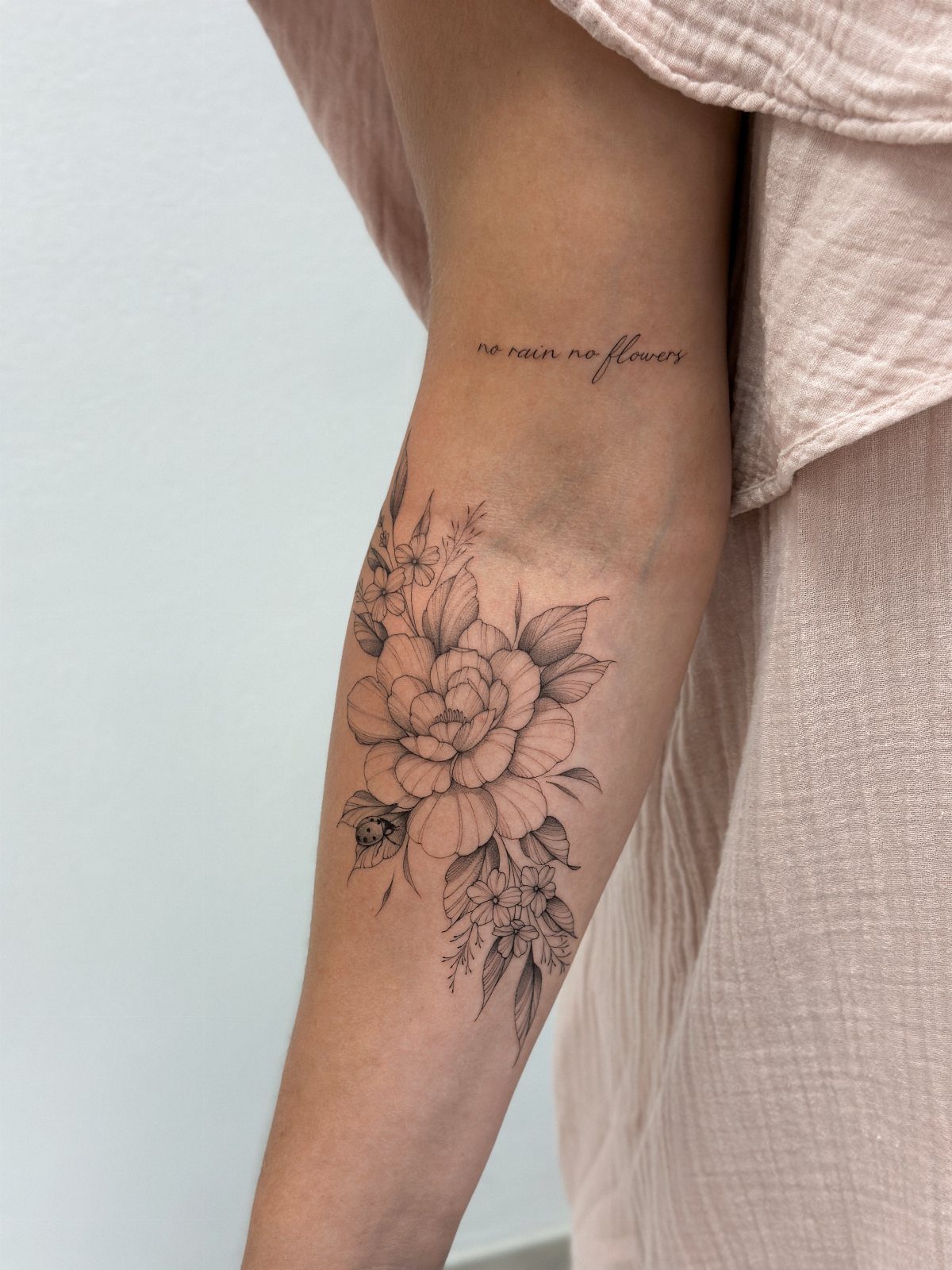 Floral peony tattoo with fine lines on a person's upper arm and shoulder.