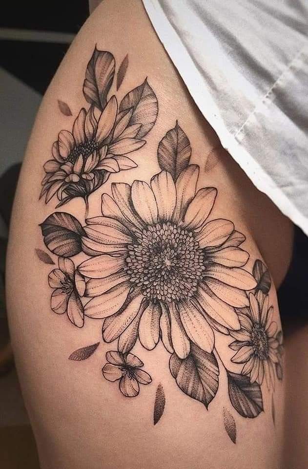 Large sunflower tattoo with smaller blossoms and leaves on a person's thigh.
