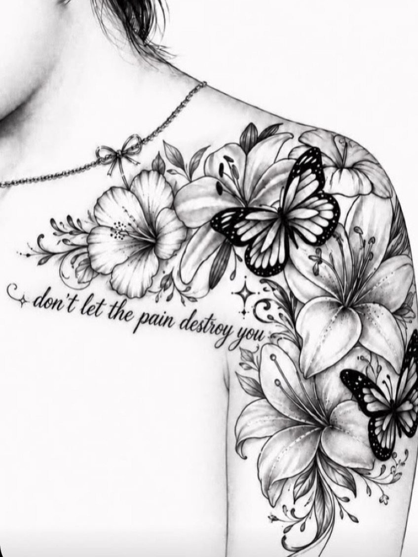 Butterfly and lily tattoo on a shoulder with cursive inspirational text quote.