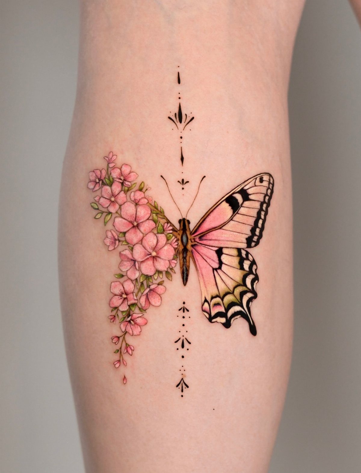 Half butterfly half flower tattoo with pink blossoms and a detailed wing.
