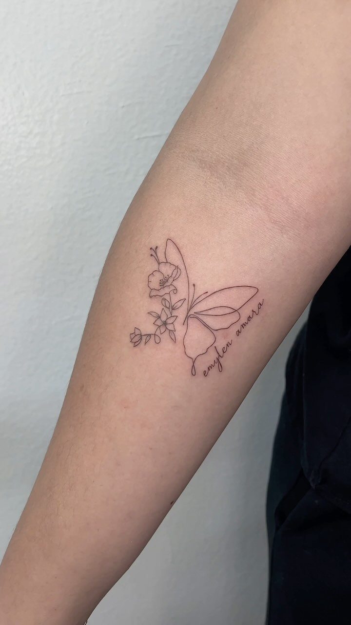 Fine-line tattoo of a butterfly and flowers with cursive text on a forearm