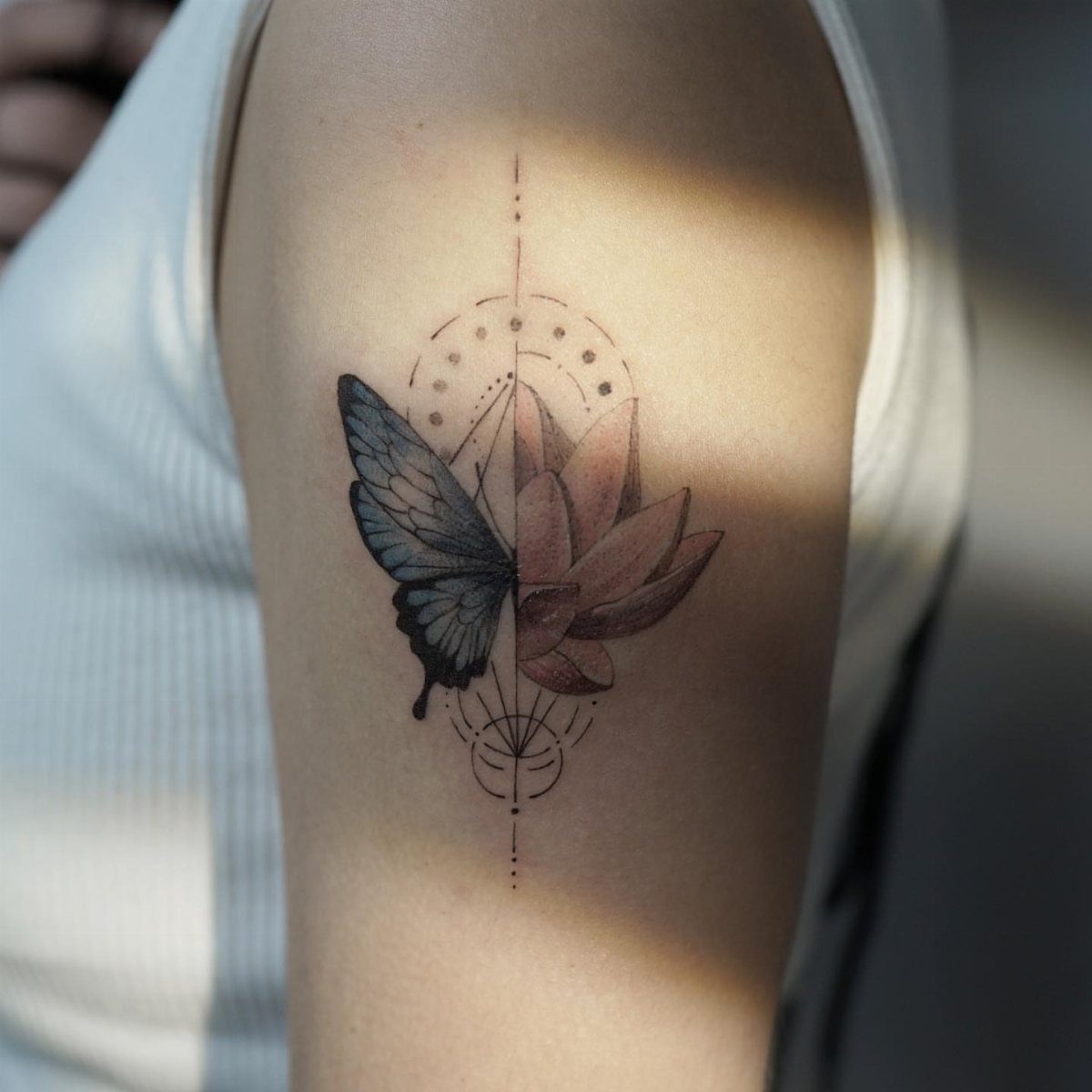 Tattoo on an arm showing a split blue butterfly and pink lotus flower design.