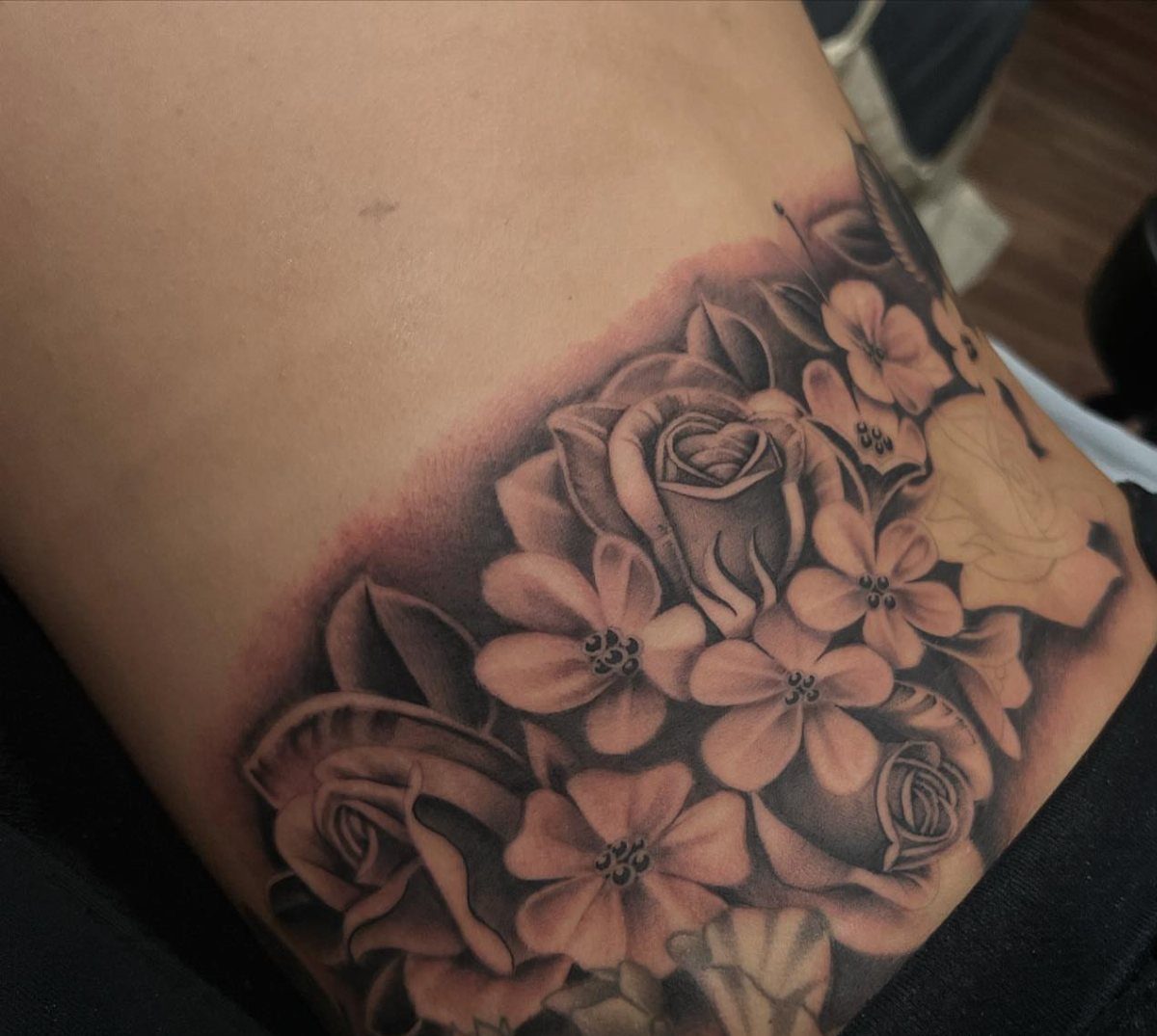 Detailed black and grey rose tattoo with heavy shading on a person's back