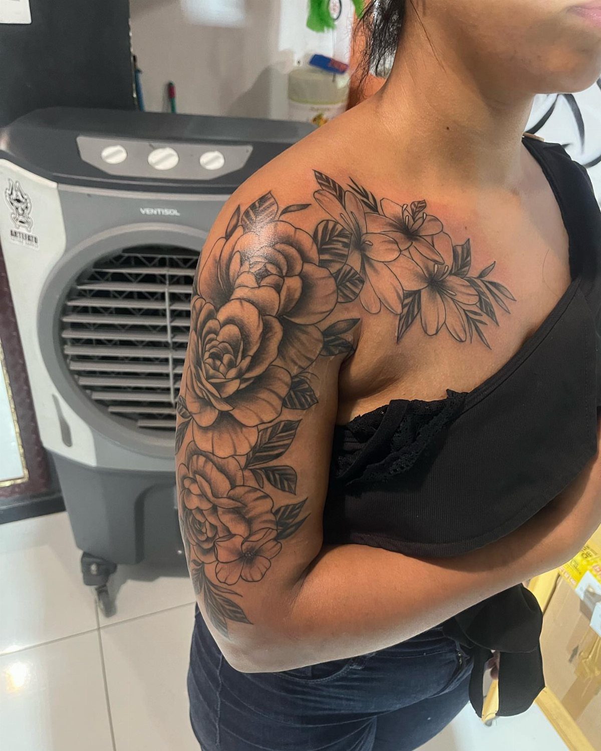 Floral rose tattoo covering the shoulder and upper arm of a person.