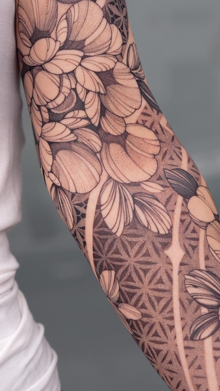 Sleeve tattoo featuring a geometric flower of life pattern and large floral elements.