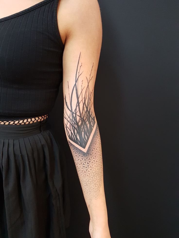 Forearm tattoo combining a geometric flower of life pattern with thin tree branches.