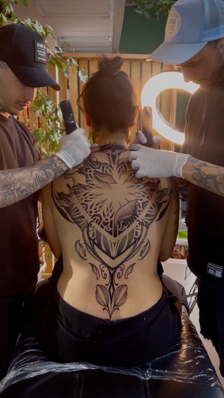 Woman with a large geometric floral tattoo extending down her spine in a studio