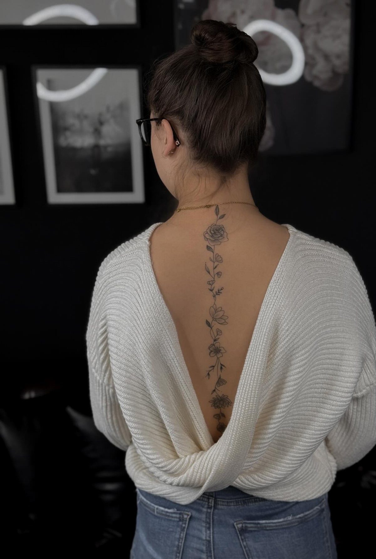 Woman with a vertical rose flower tattoo running down her spine