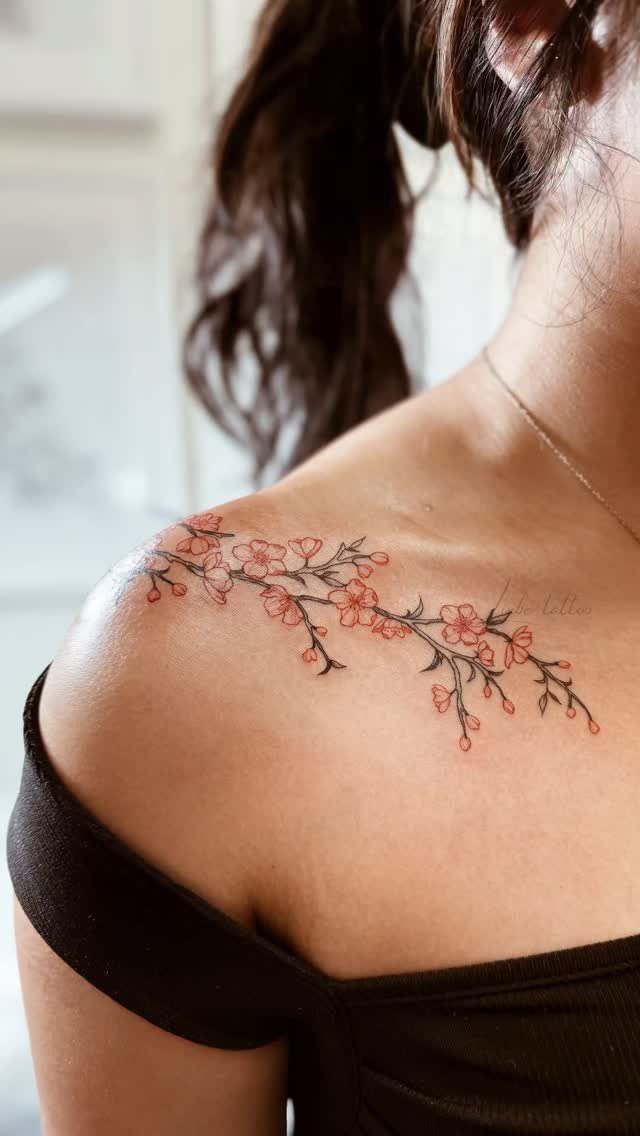 Cherry blossom branch tattoo with pink flowers on a person's shoulder.