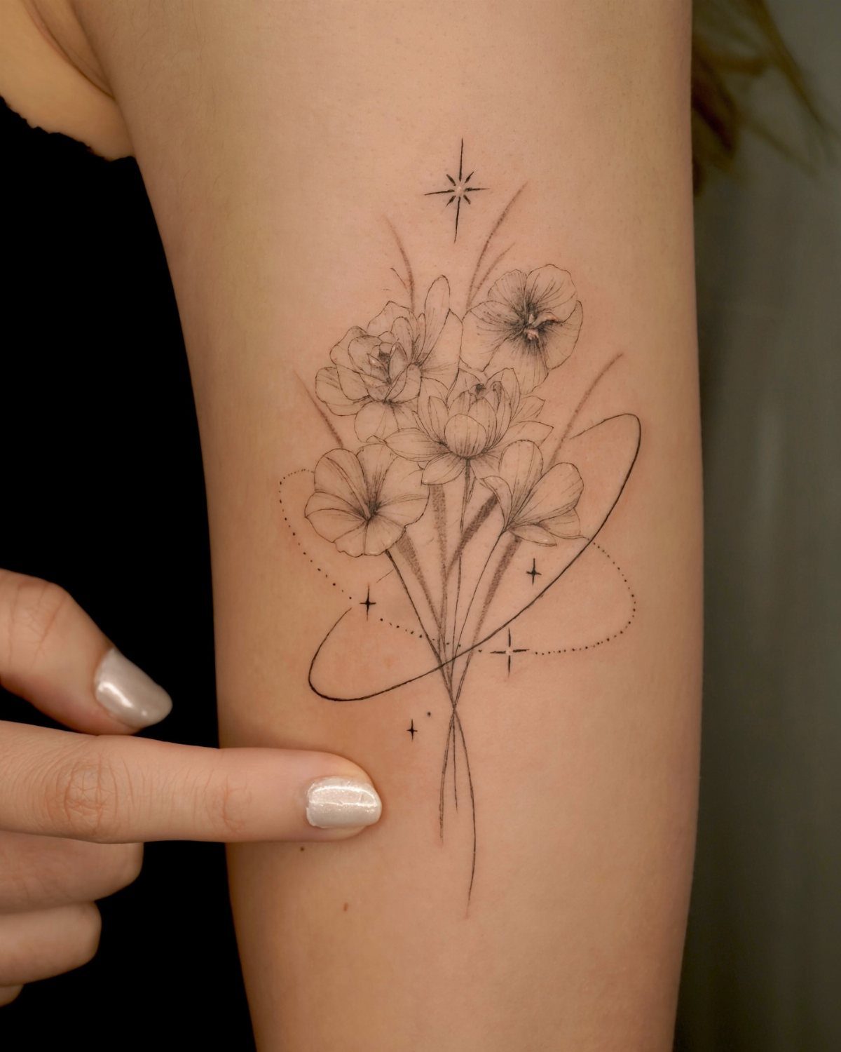 Fine line floral tattoo of a flower bouquet on a person's arm.