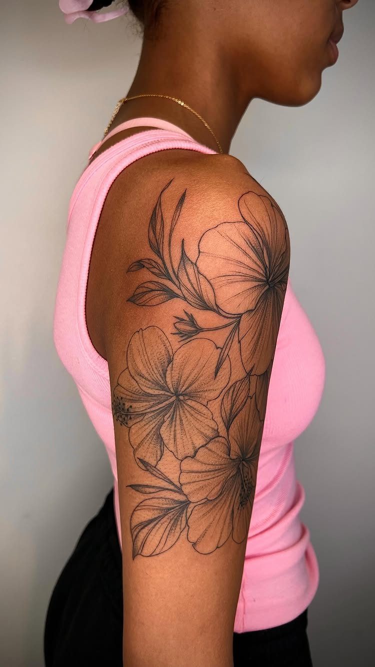 Hibiscus flower tattoo with black outlines on a person's upper arm.