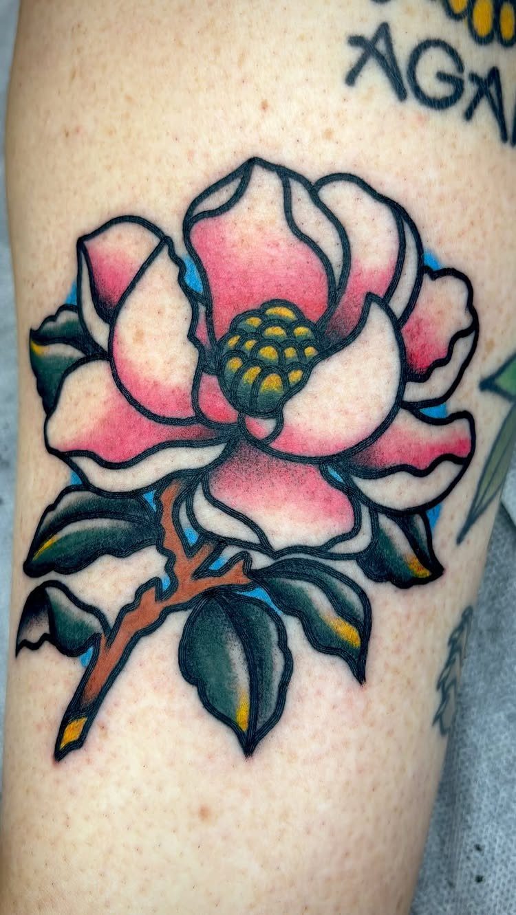 Magnolia flower tattoo with pink petals and green leaves on skin