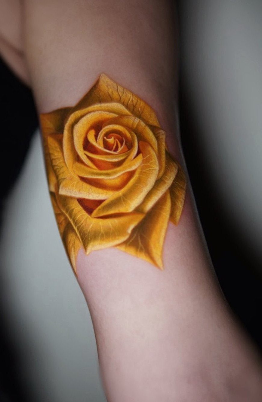 Yellow rose tattoo with detailed shading on a person's forearm