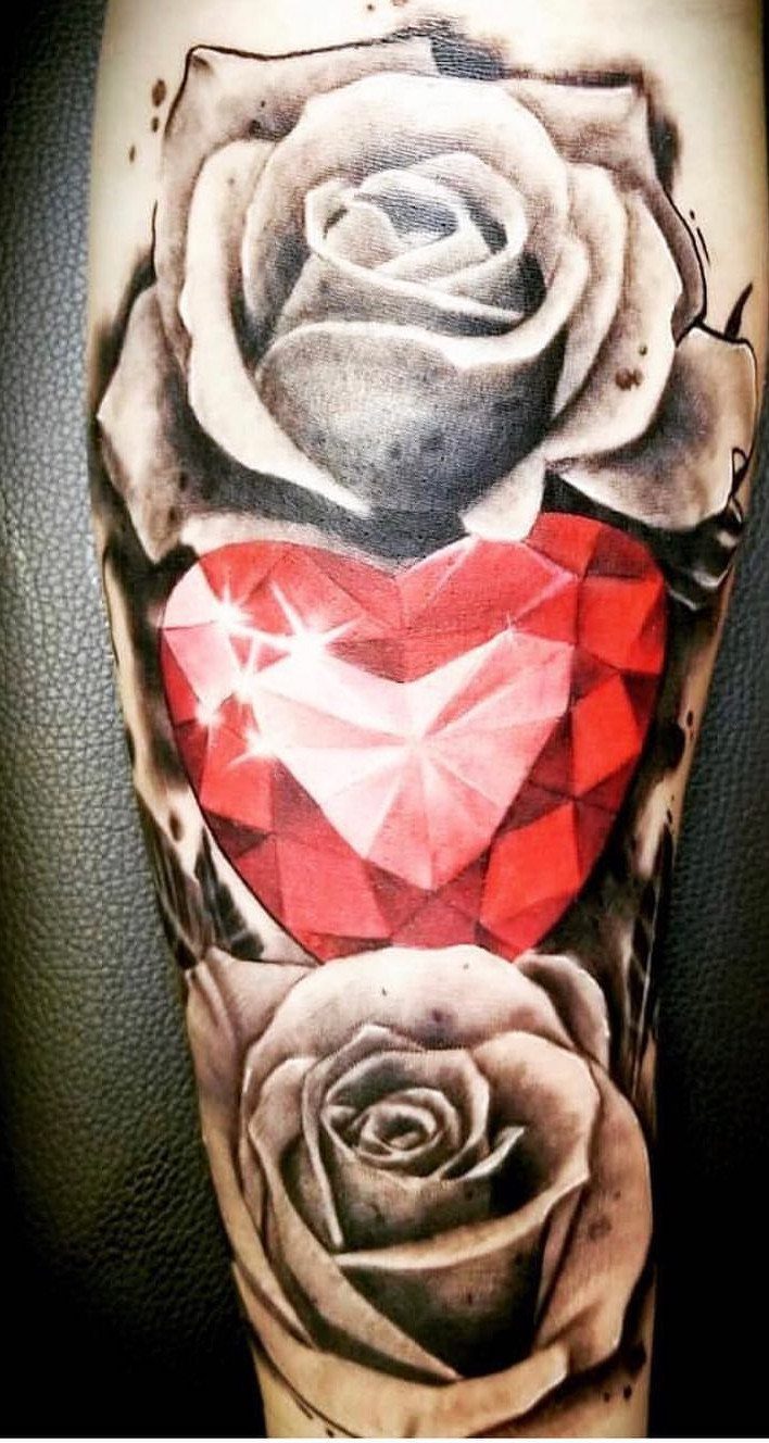 Tattoo of two grey roses surrounding a large faceted red heart diamond
