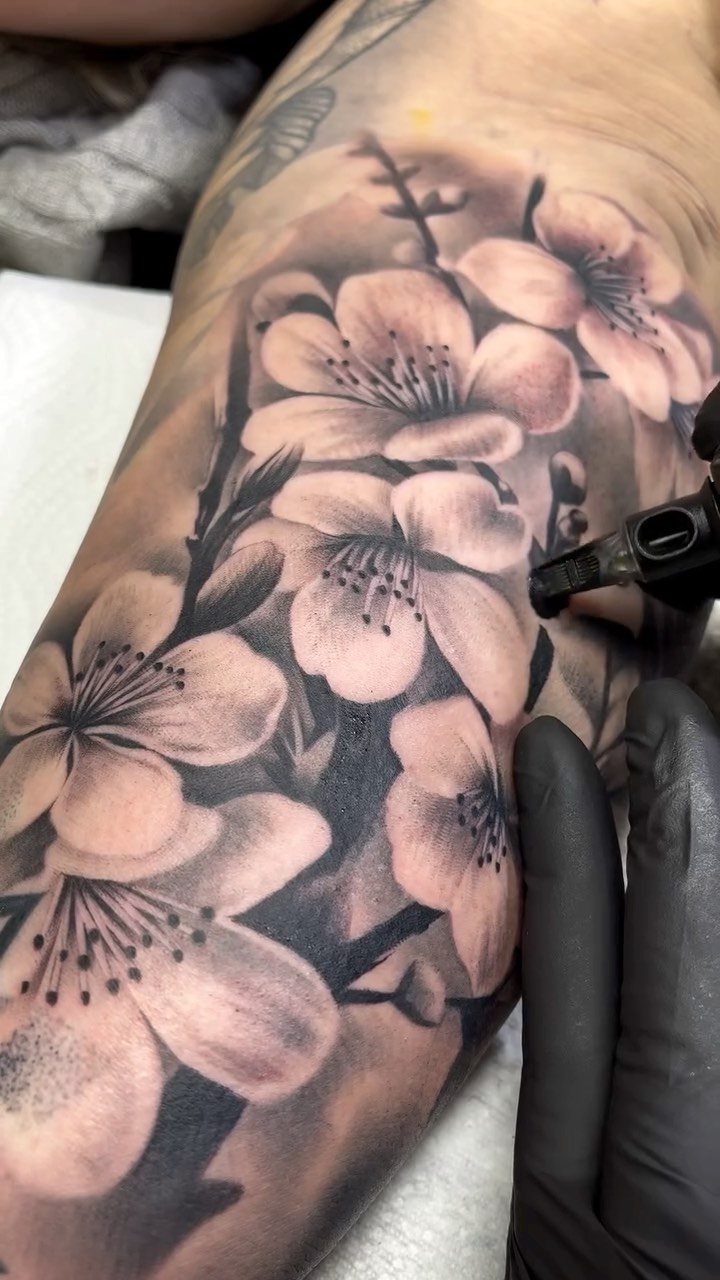 Cherry blossom tattoo on a hip being worked on by a tattoo artist