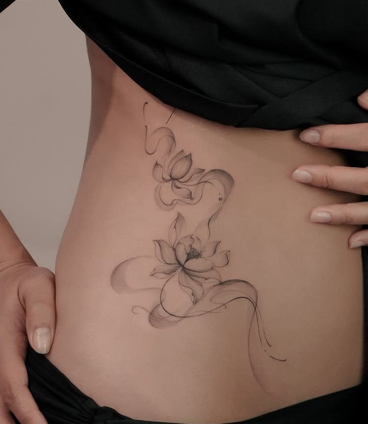 Lotus flower tattoo with flowing lines on a person's hip and waist