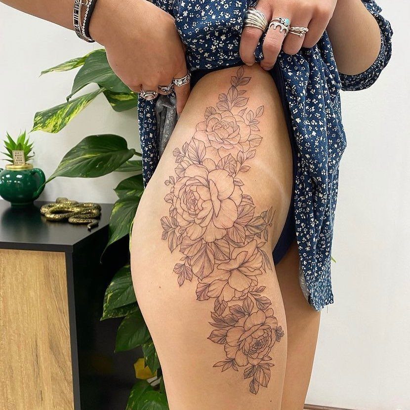 Rose flower tattoo on a person's hip and upper thigh with detailed linework.