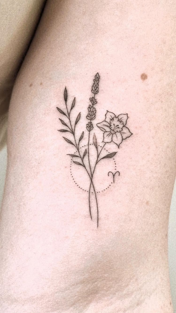 Floral outline tattoo with a zodiac symbol on a person's skin