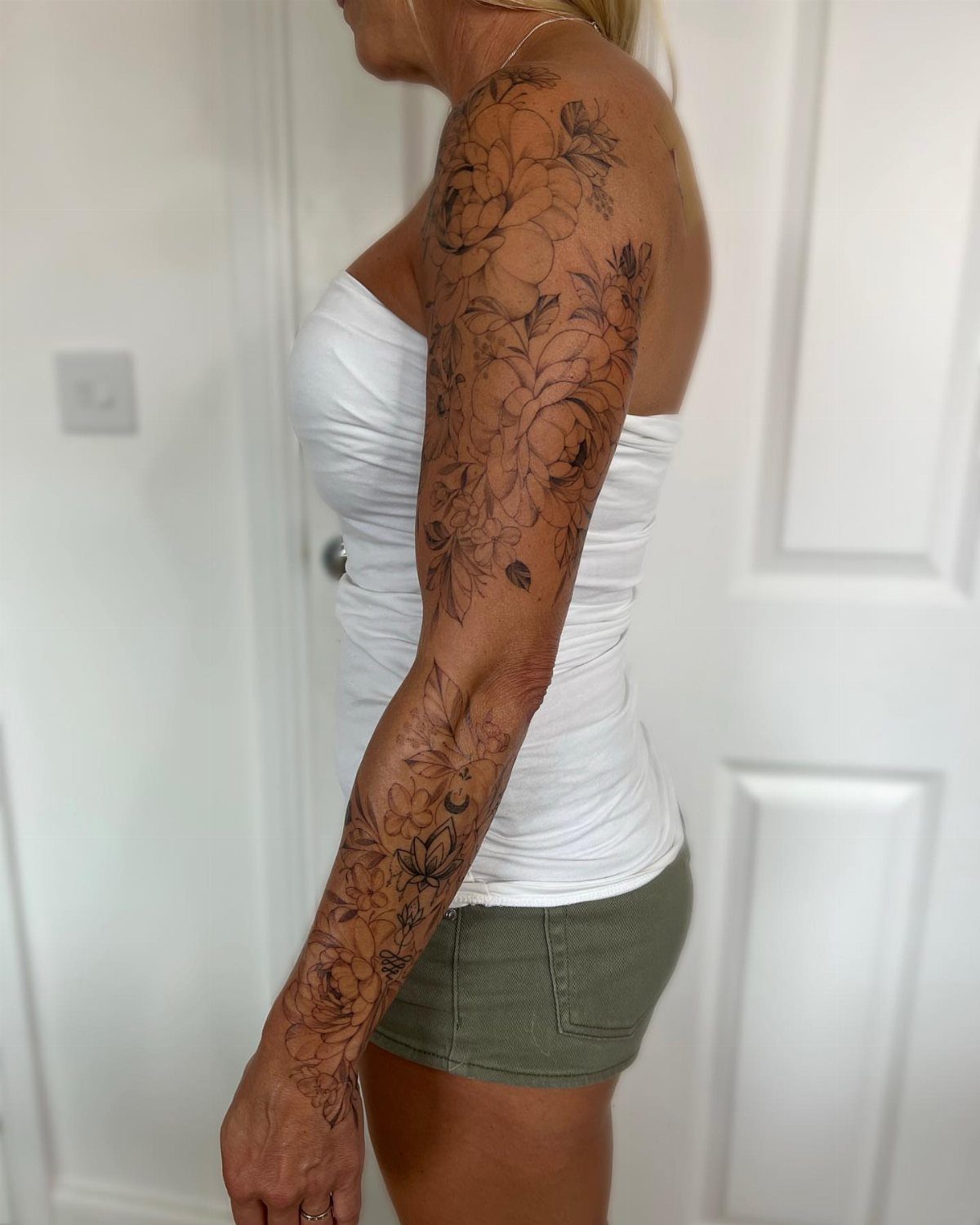 Floral outline tattoo covering a woman's entire arm from shoulder to wrist.