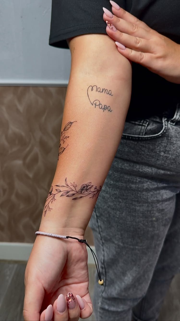 Floral vine tattoo wrapping around a person's wrist and forearm in black ink