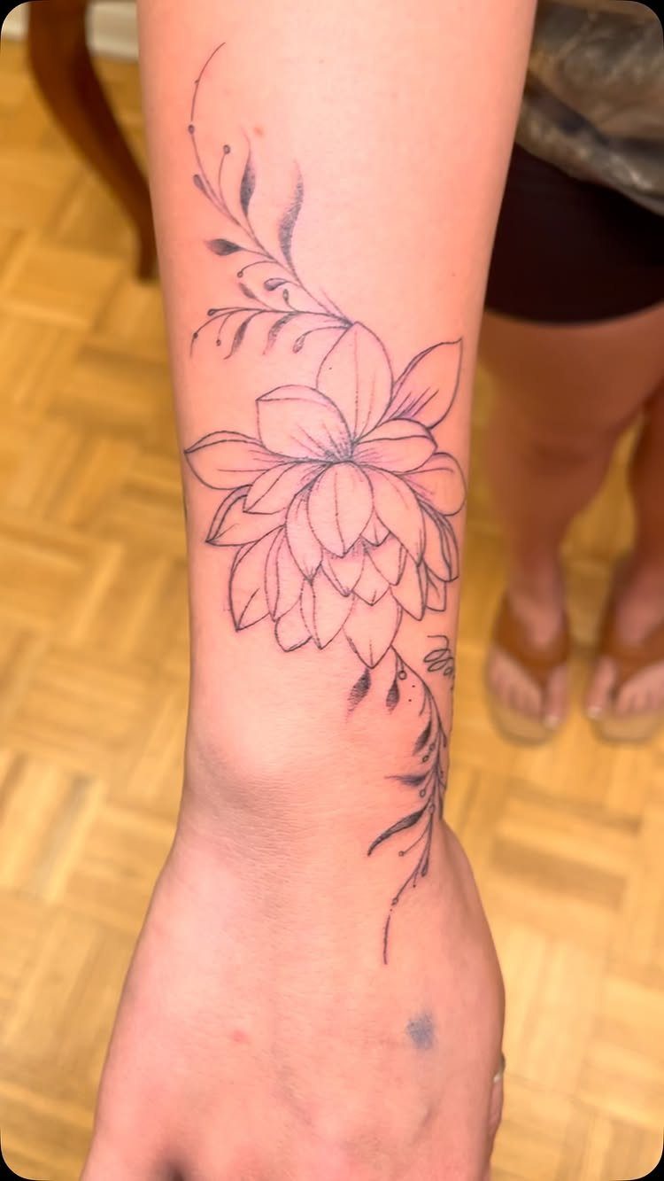 Lotus flower tattoo with purple lines on a person's inner wrist and forearm.