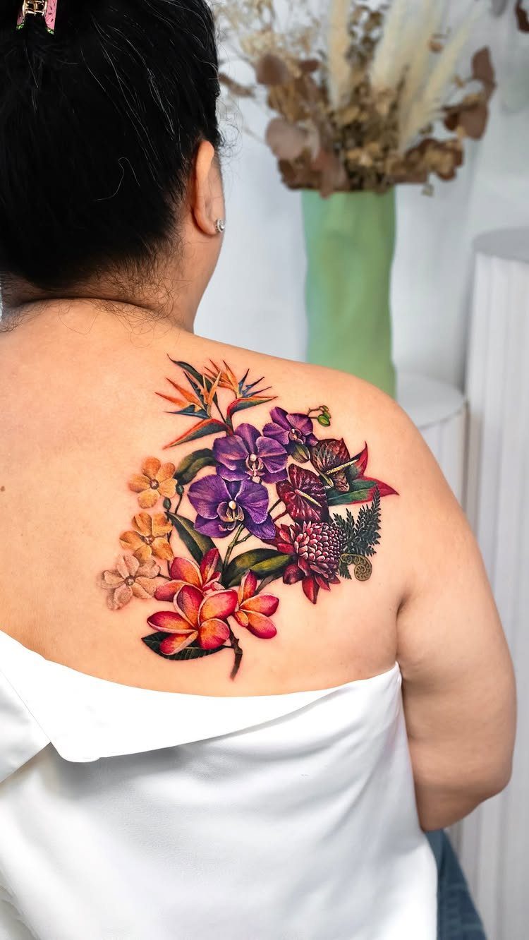 Colorful tropical flower tattoo on a person's back featuring purple orchids and plumeria.