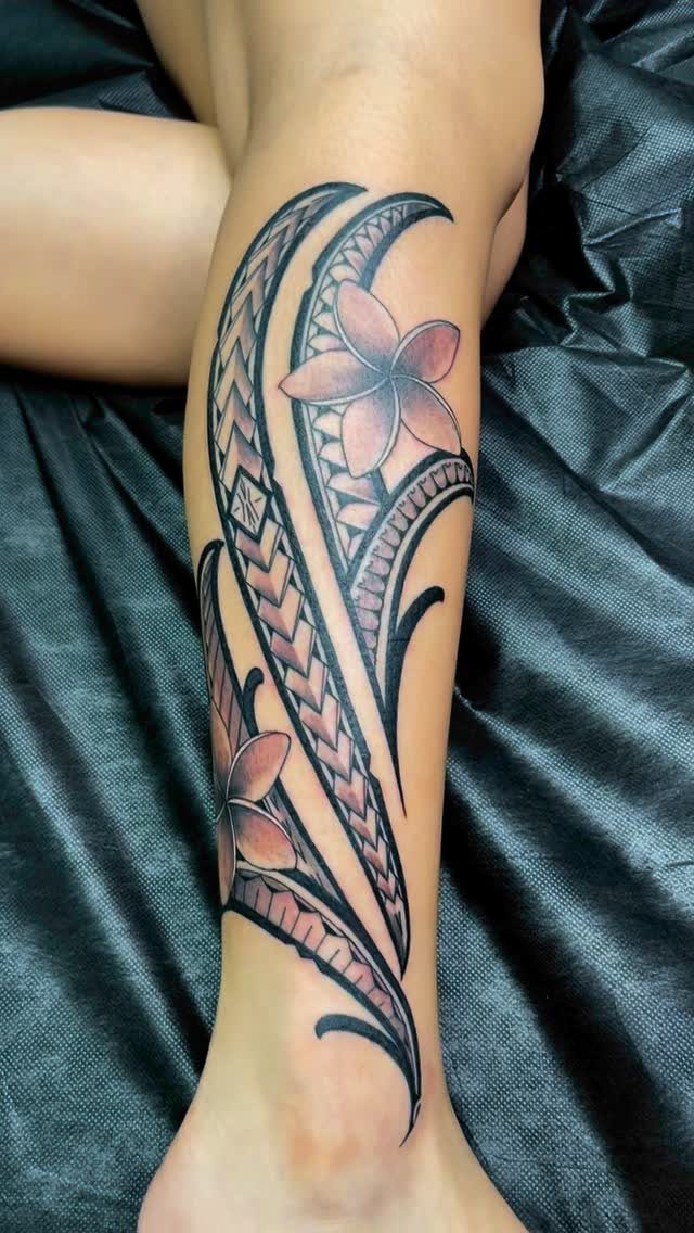 Plumeria flower tattoo with black tribal patterns on a person's lower leg.