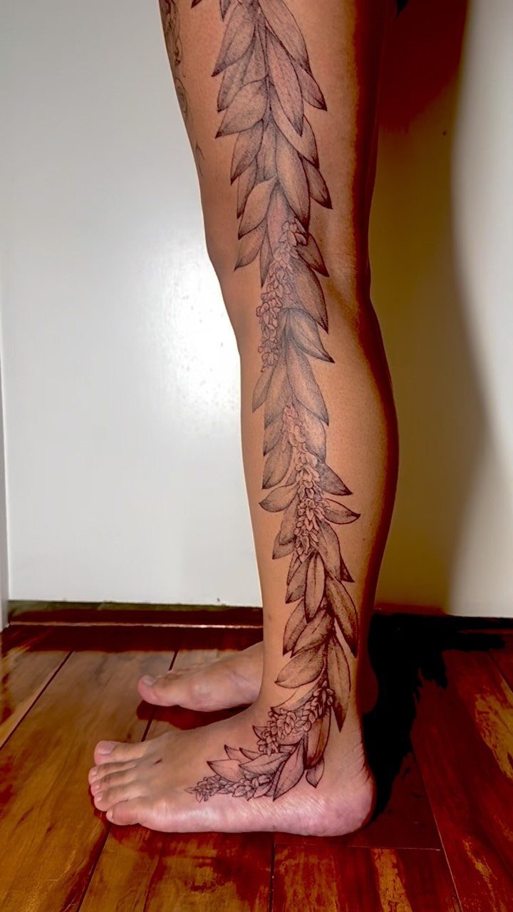 Tropical floral vine tattoo extending down a person's leg to their foot.