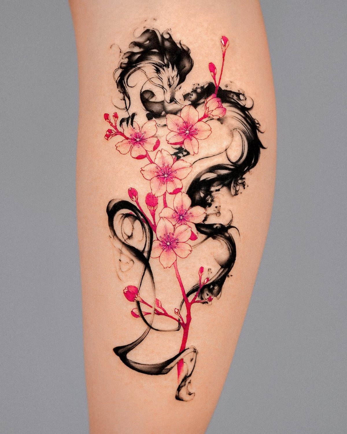 Cherry blossom tattoo with pink flowers and black ink swirls on skin