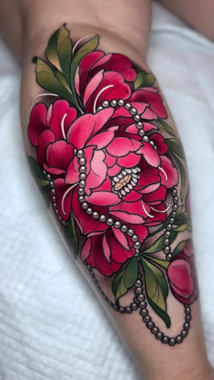 Pink peony flower tattoo with green leaves and pearls on a leg