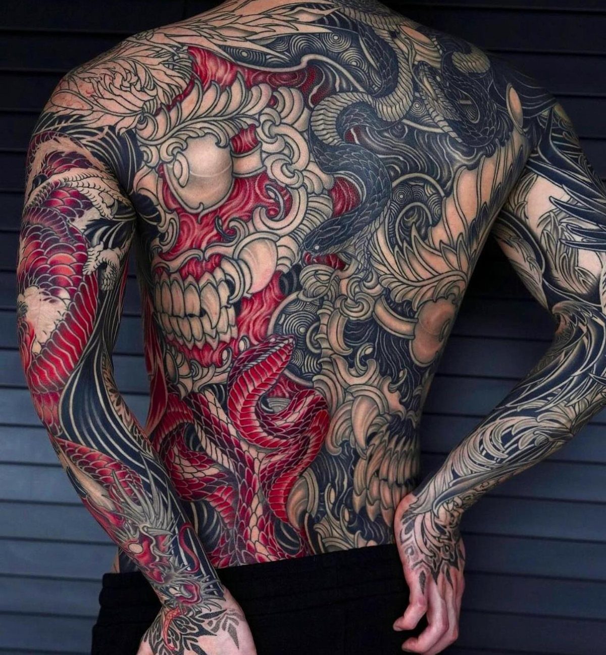 Man's back and arms with a large red skull and snake Japanese tattoo.