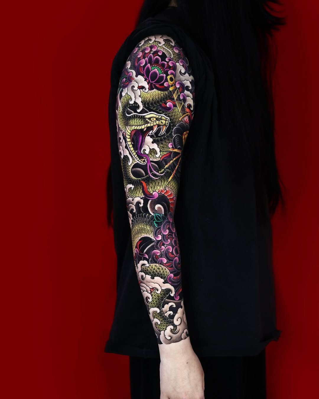 Green Japanese snake tattoo sleeve with purple clouds and pink flowers on arm