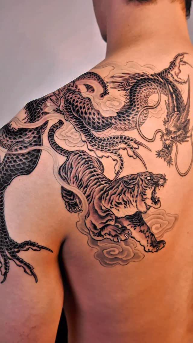 Japanese style tattoo of a tiger and dragon on a man's shoulder