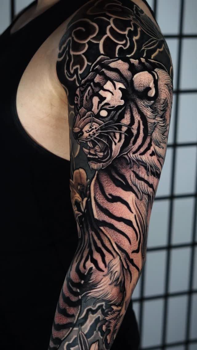 Japanese tiger tattoo covering a person's shoulder and upper arm sleeve.