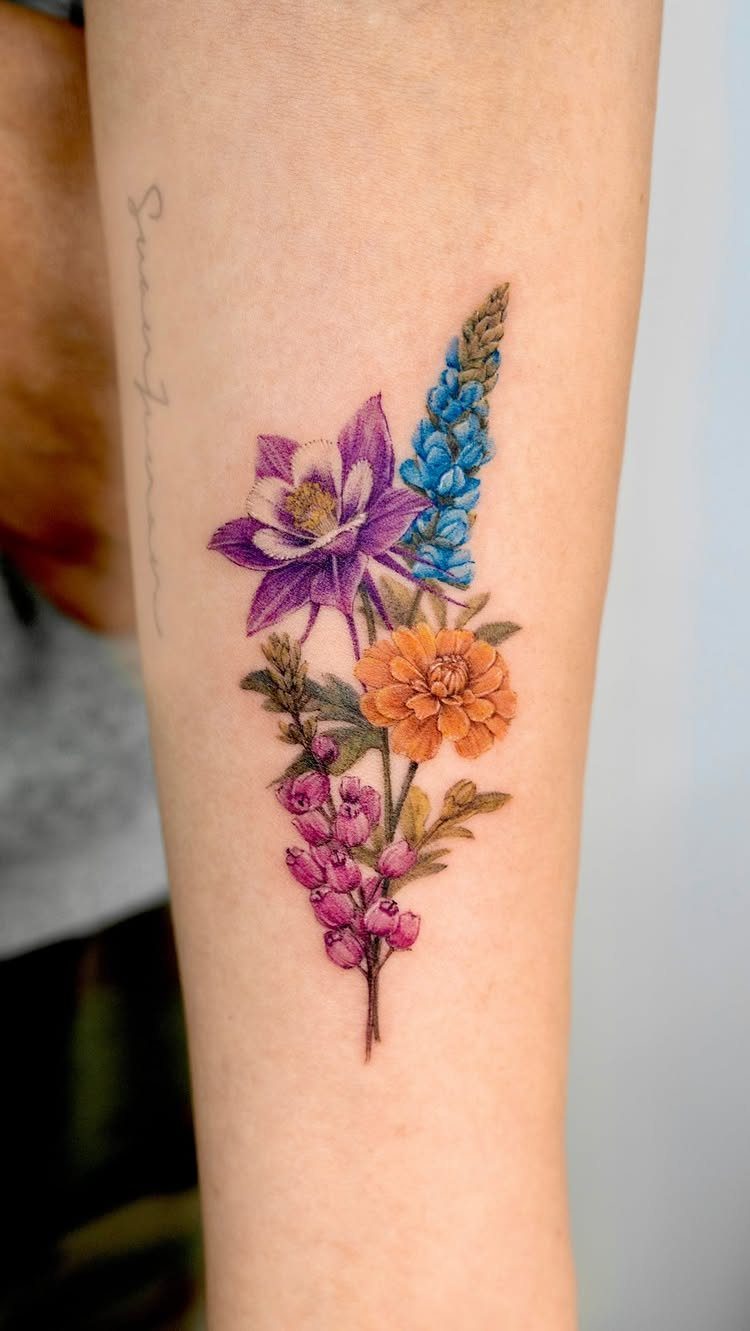 Colorful floral bouquet tattoo on a forearm featuring purple, blue, and orange blooms.