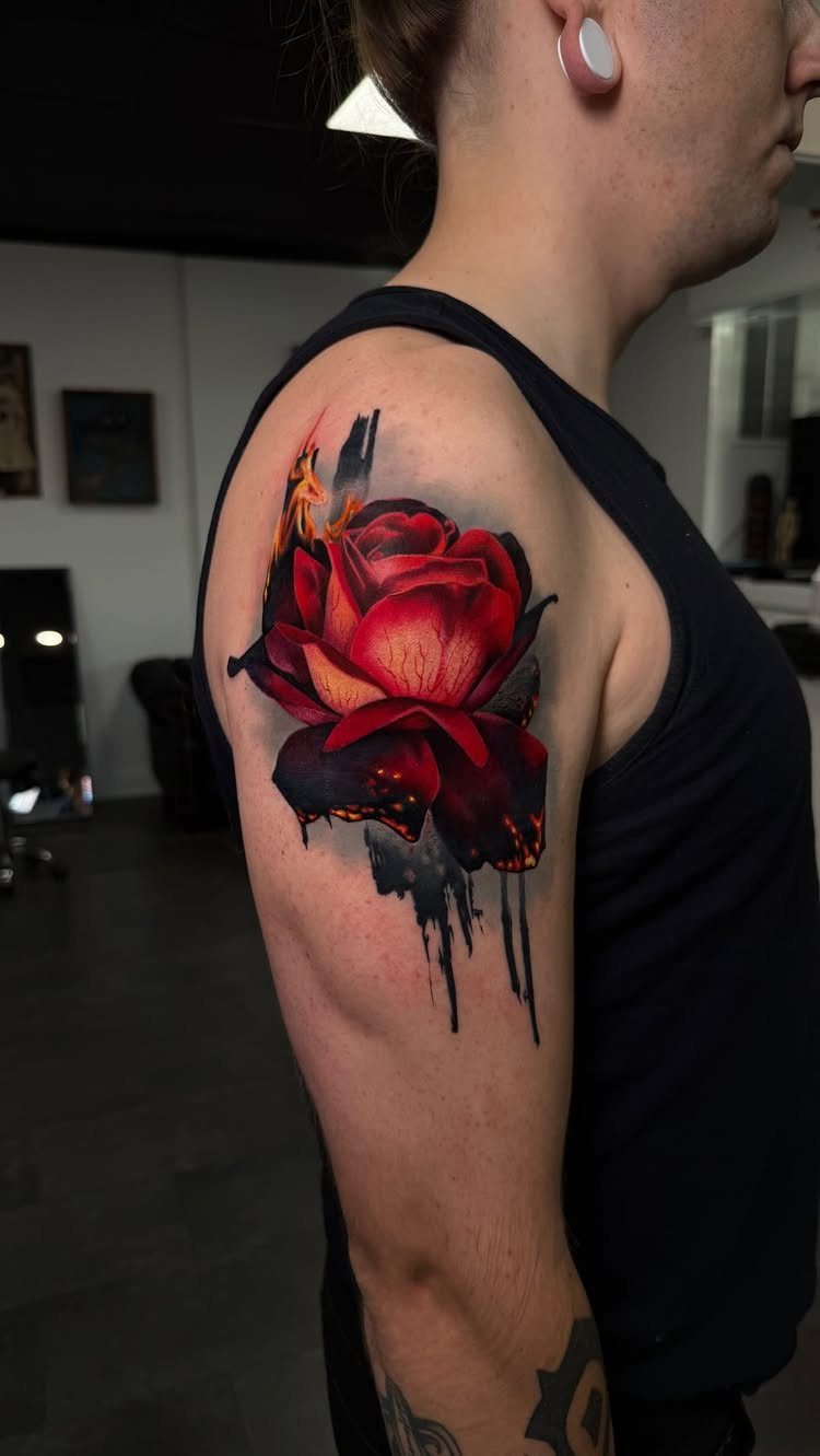 Realistic red rose tattoo with black ink drips on a person's upper arm