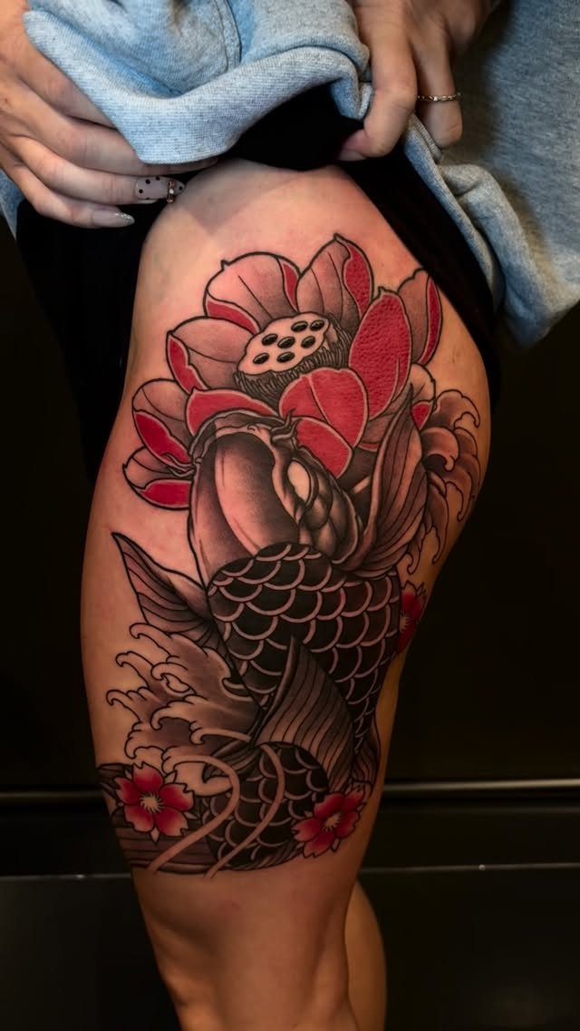 Koi fish tattoo on a thigh with a red lotus and cherry blossoms