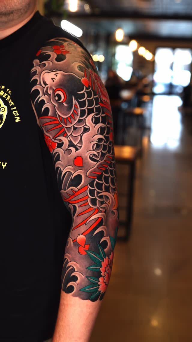 Traditional red and grey koi fish tattoo on a man's upper arm