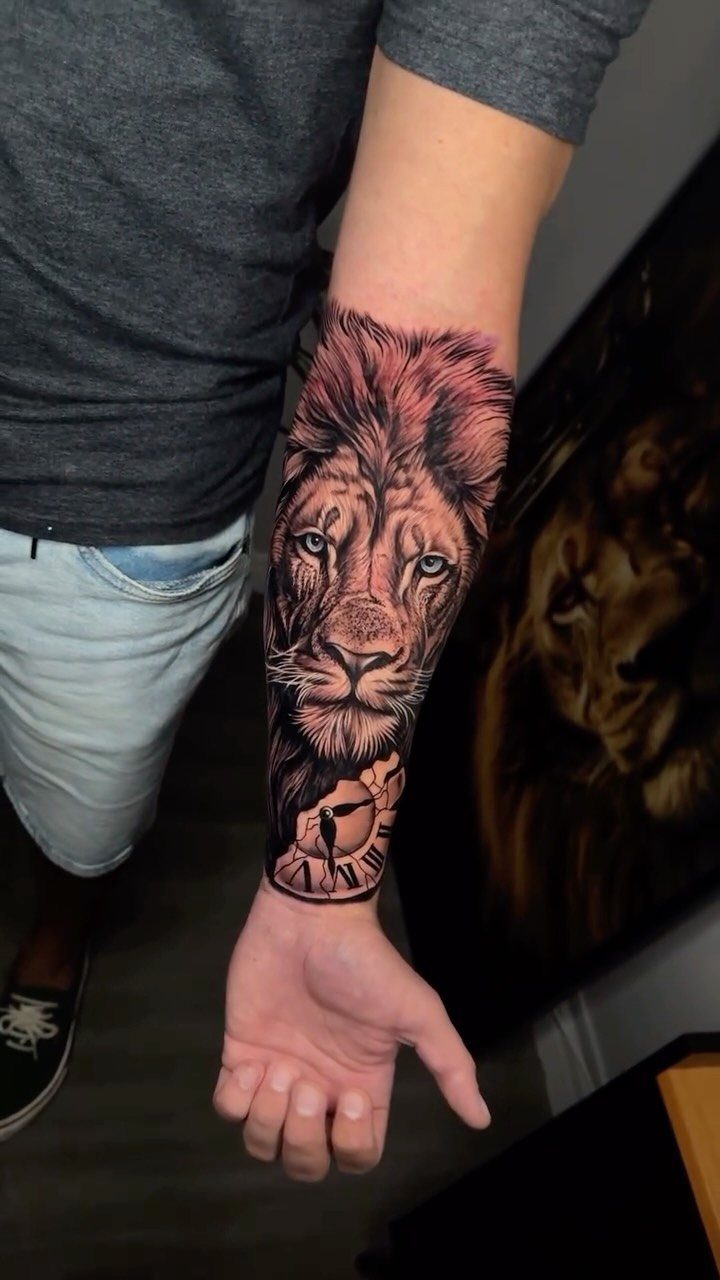 Detailed black and grey lion and clock tattoo on a person's forearm