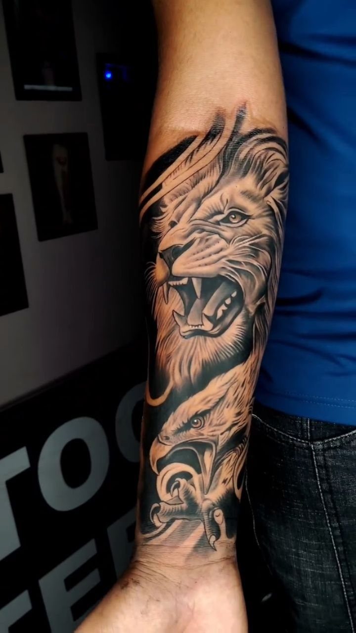 Roaring lion and eagle tattoo in black and grey ink on a forearm