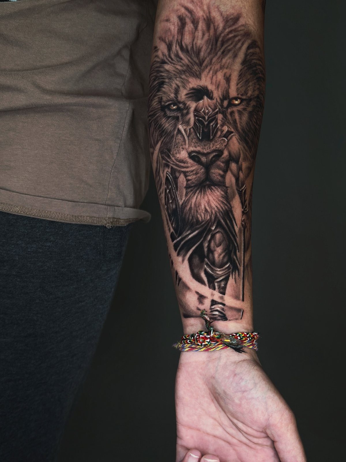 Detailed black and grey lion tattoo on a person's forearm with realistic shading.