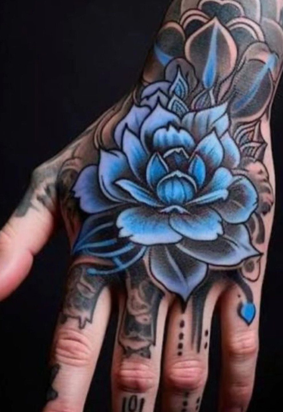 Blue lotus flower tattoo covering the back of a person's hand and fingers.