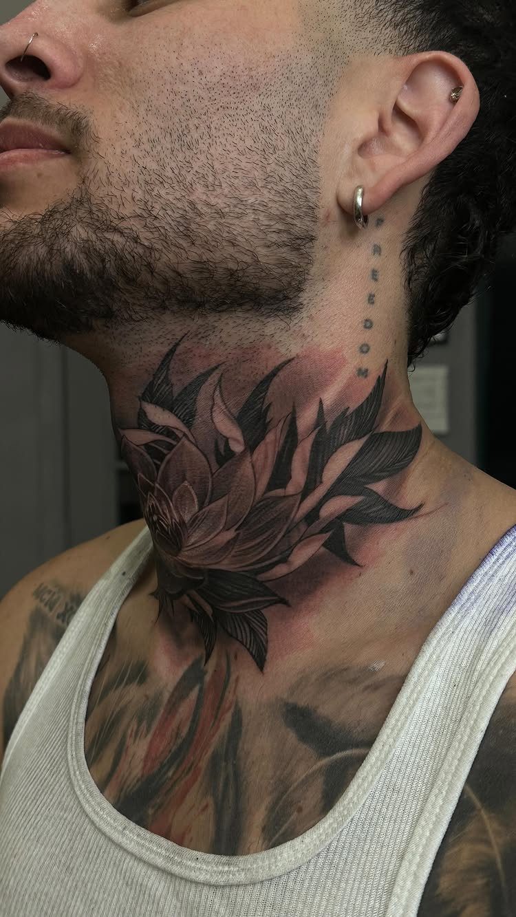 Lotus flower tattoo on a man's neck with detailed black and grey shading.